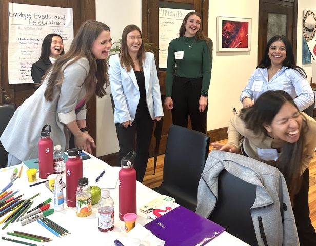 College students laughing around a conference table in a workshop at Banktastic