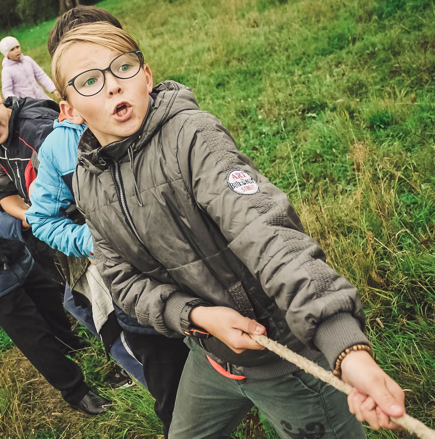 Young blonde girl pulling on a rope in a game of tug of war