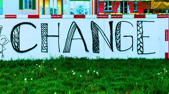 hand painted black graffitti on a white wall spelling out the word CHANGE